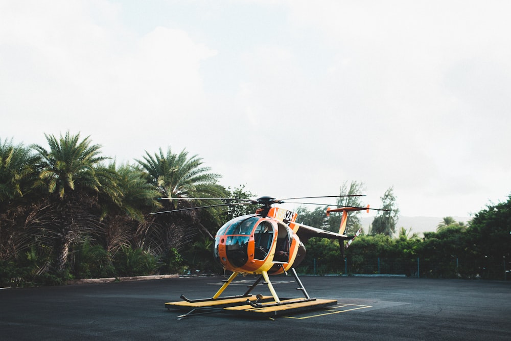昼間の地上のオレンジと黄色のヘリコプター