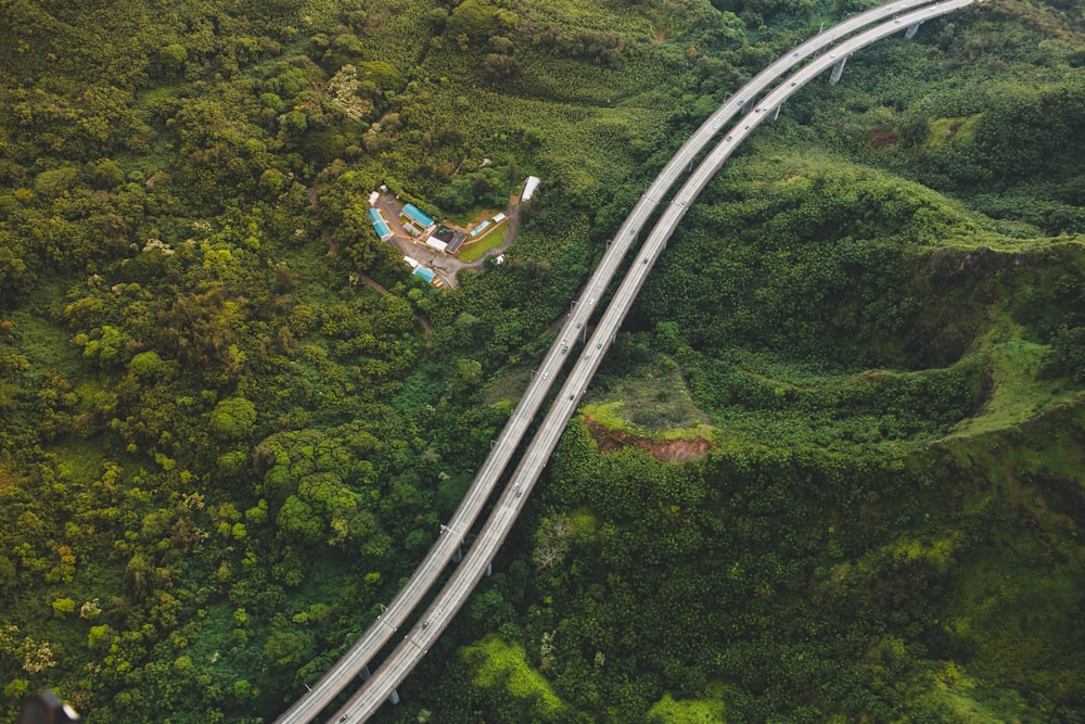 A drone shot of a two-lane road on forested hills