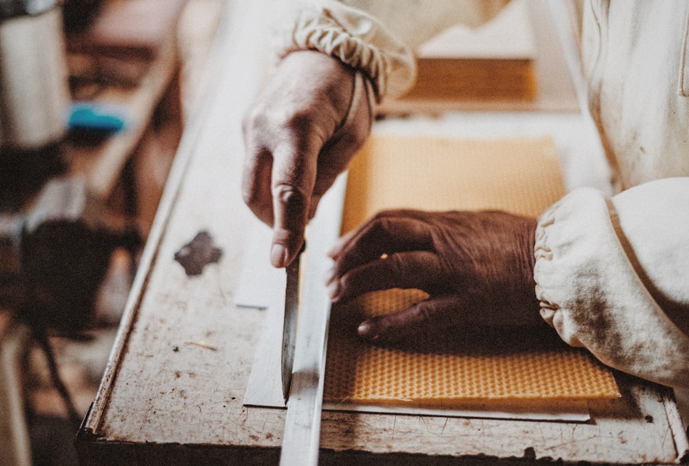 person holding chisel while carving wood