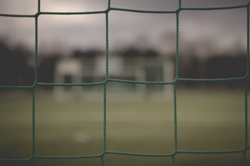 Close-up of green sports netting stretched tightly on a soccer field under bright sunlight