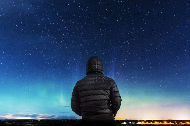 A sleek black jacket with glowing blue constellation patterns under a starry night sky.