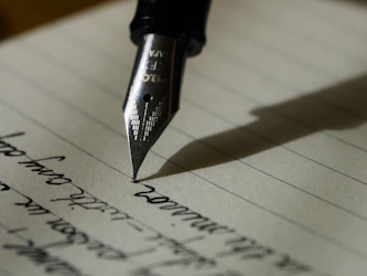Person writing with pen on paper for grammar and writing improvement guides
