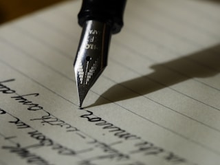 A fountain pen writing on lined paper