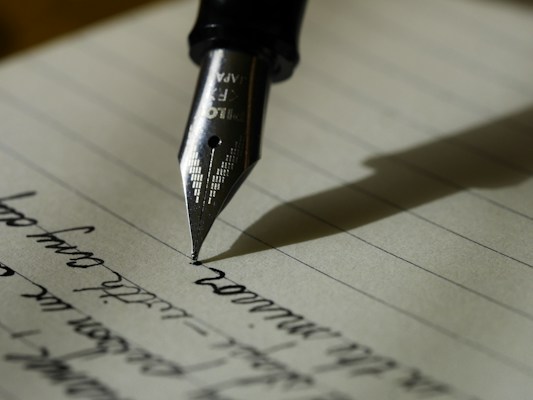 Writer working on laptop composing an essay using word counter tool to track text length