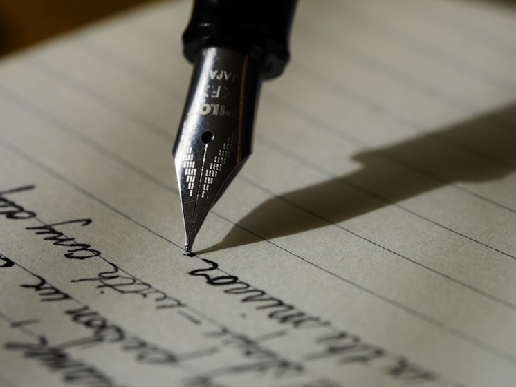 Mani che scrivono su un taccuino con penna stilografica