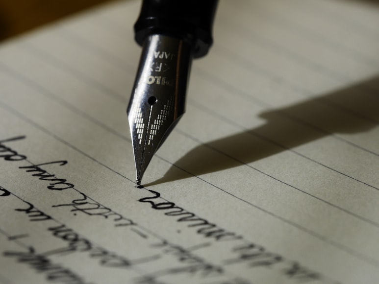 A person writing on paper with a pen