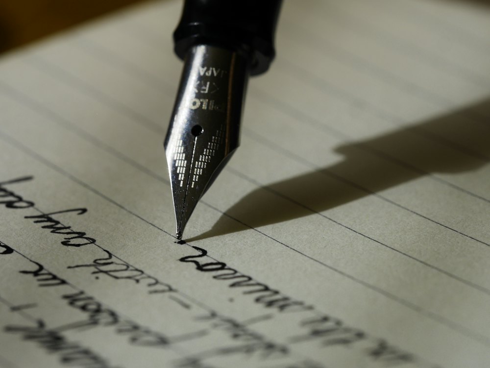 Writer planning articles in a notebook beside a laptop