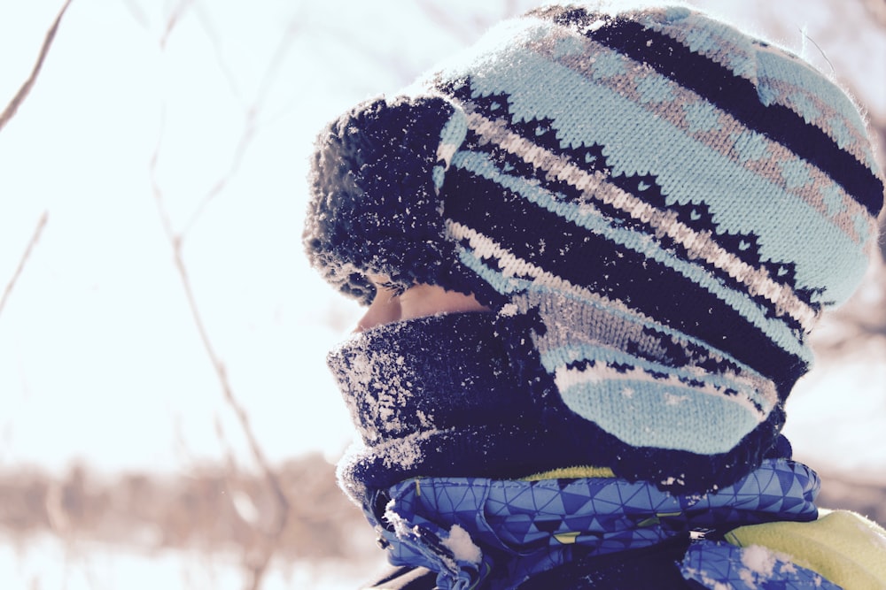 Person mit schwarz-blaugrün gestreifter Mütze bei Schneezeit
