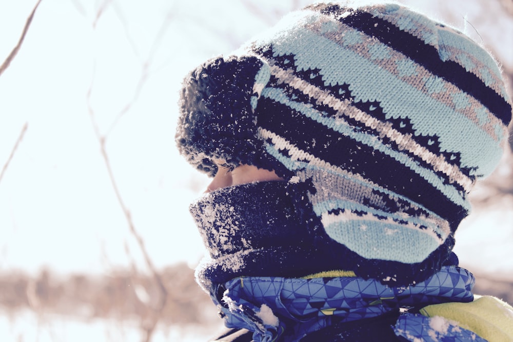 Persona che indossa un cappello a strisce nere e verde acqua al momento della neve