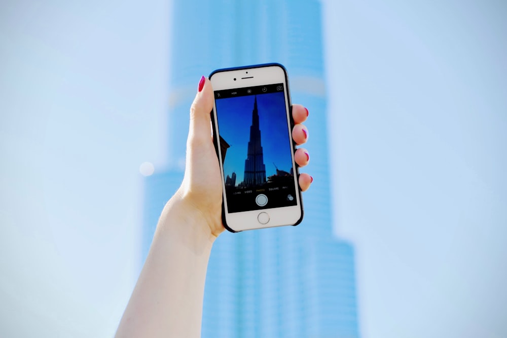 person holding silver iPhone 6 and black case