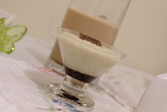 Elegant glass filled with layered Dubai-style chocolate dessert topped with nuts and gold flakes.