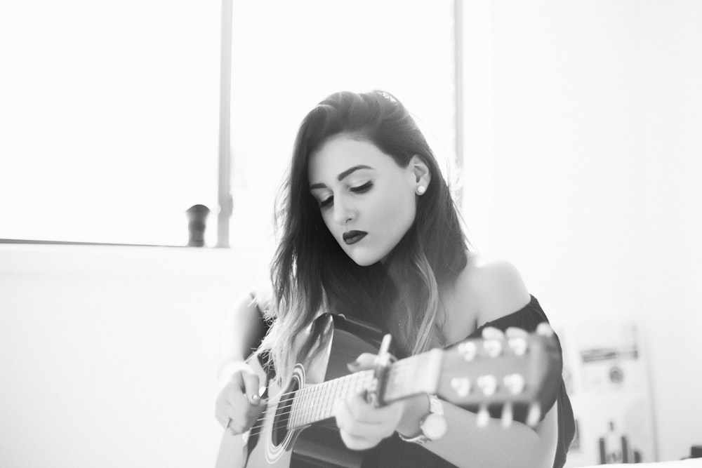 grayscale photography of woman play guitar