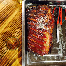 Grilled beef ribs glazed with a smoky sauce, served on a wooden platter.