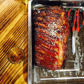 Grilled beef ribs glazed with a smoky sauce, served on a wooden platter.