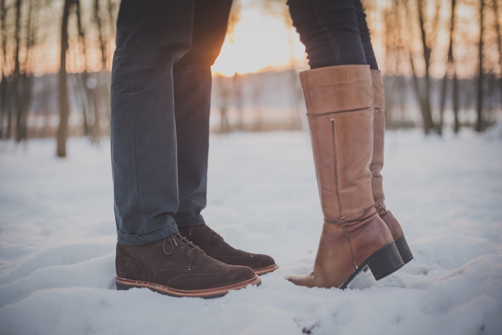 Due persone in stivali marroni e scarpe sulla foresta innevata