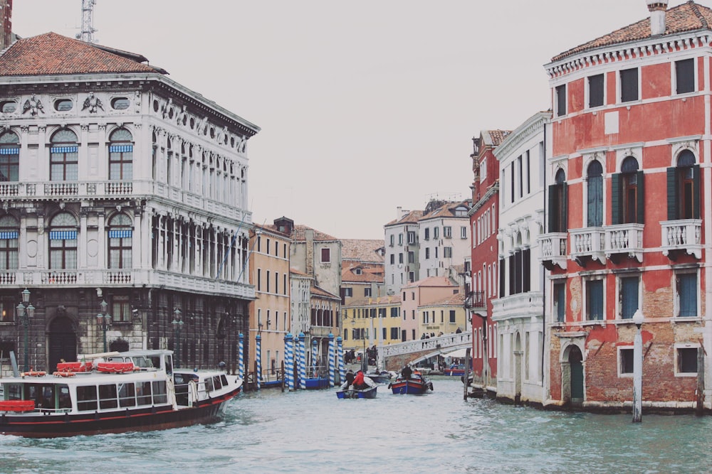 two boats on body of water between buildings