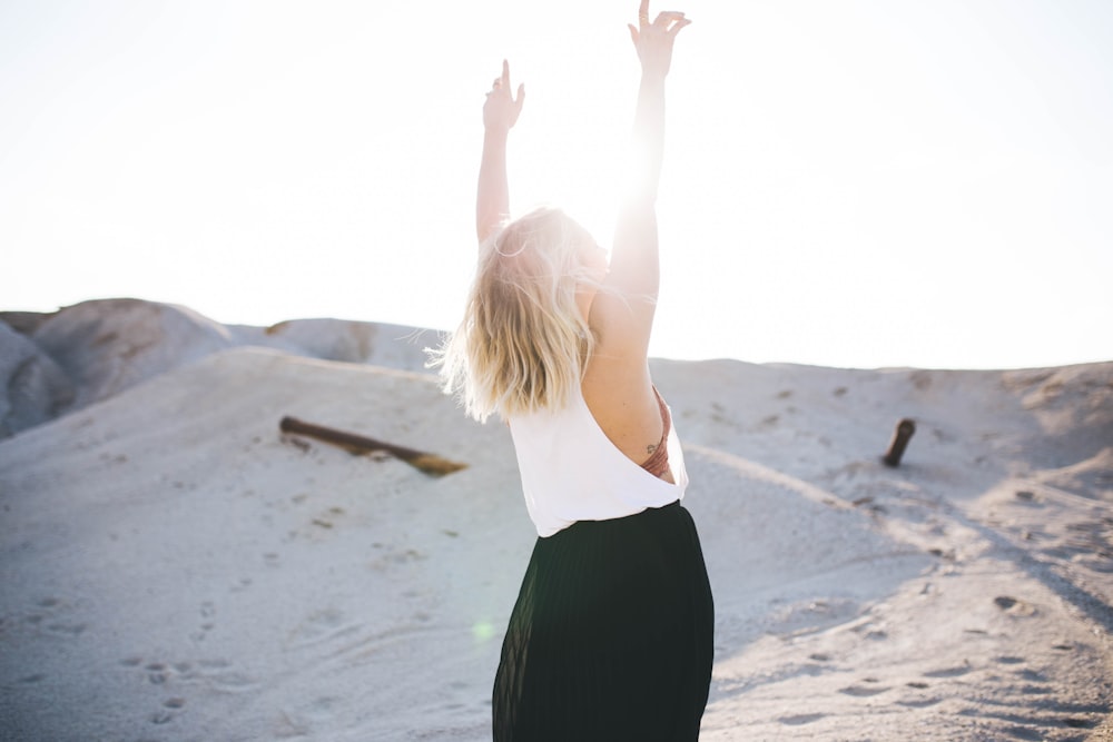 woman standing on the desert while her hands up