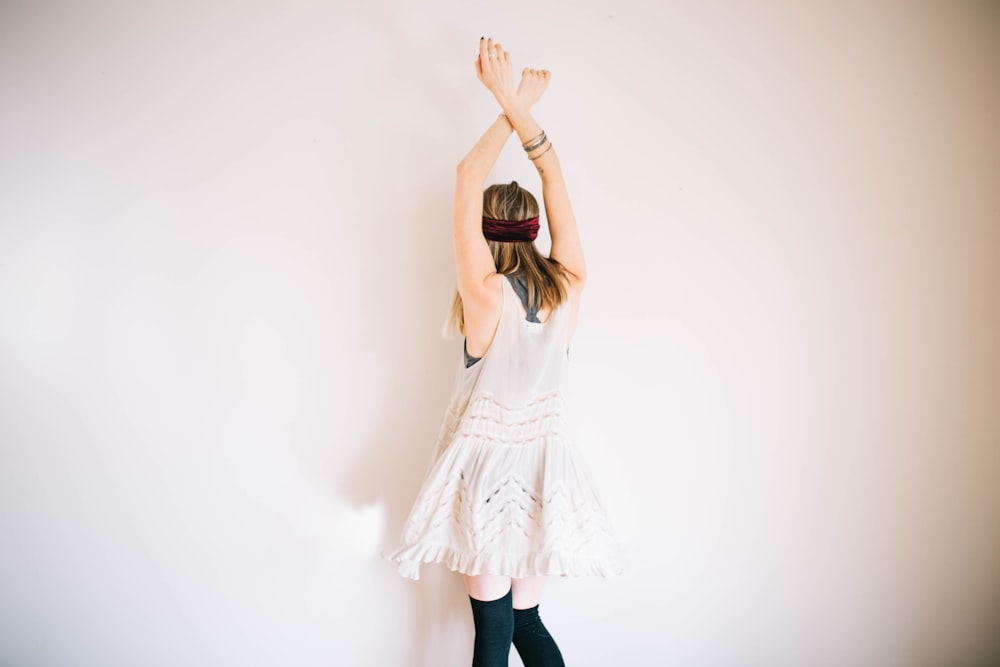 woman wearing white sleeveless top with hands above head