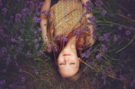 woman in yellow and teal top sleeping beside lavenders