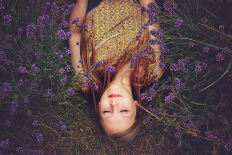 woman in yellow and teal top sleeping beside lavenders