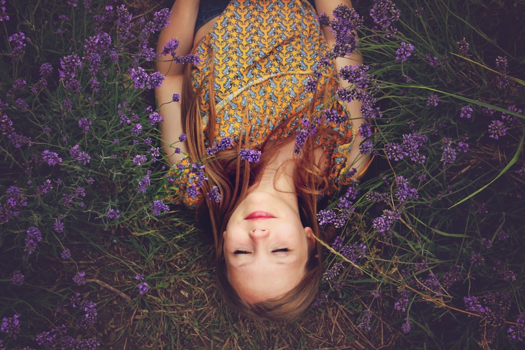 Menina deitada na natureza em meio a flores roxas