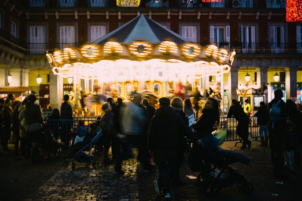 Children playing near a colorful carousel in a bustling European city square filled with laughter and light.