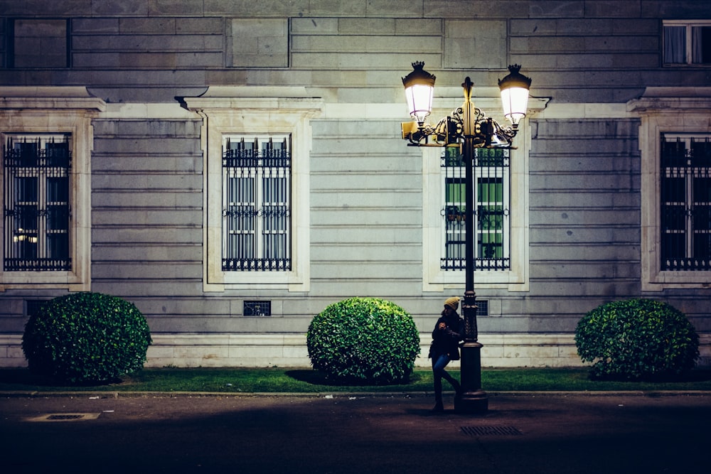 femme à côté d’un lampadaire dans la ruelle près d’un bâtiment en béton