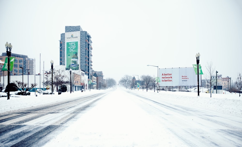snow covered road near high rise buildings during daytime