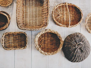Various sizes and shapes of woven wicker baskets displayed on a green garden bench