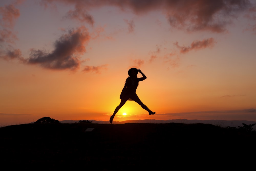 silhouette di umano che salta durante il tramonto