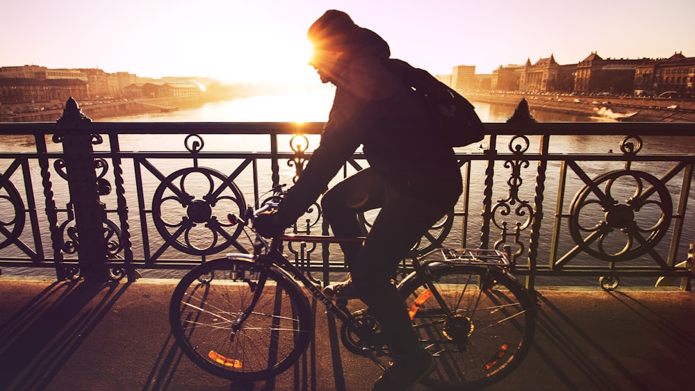 man riding bicycle in silhouette painting
