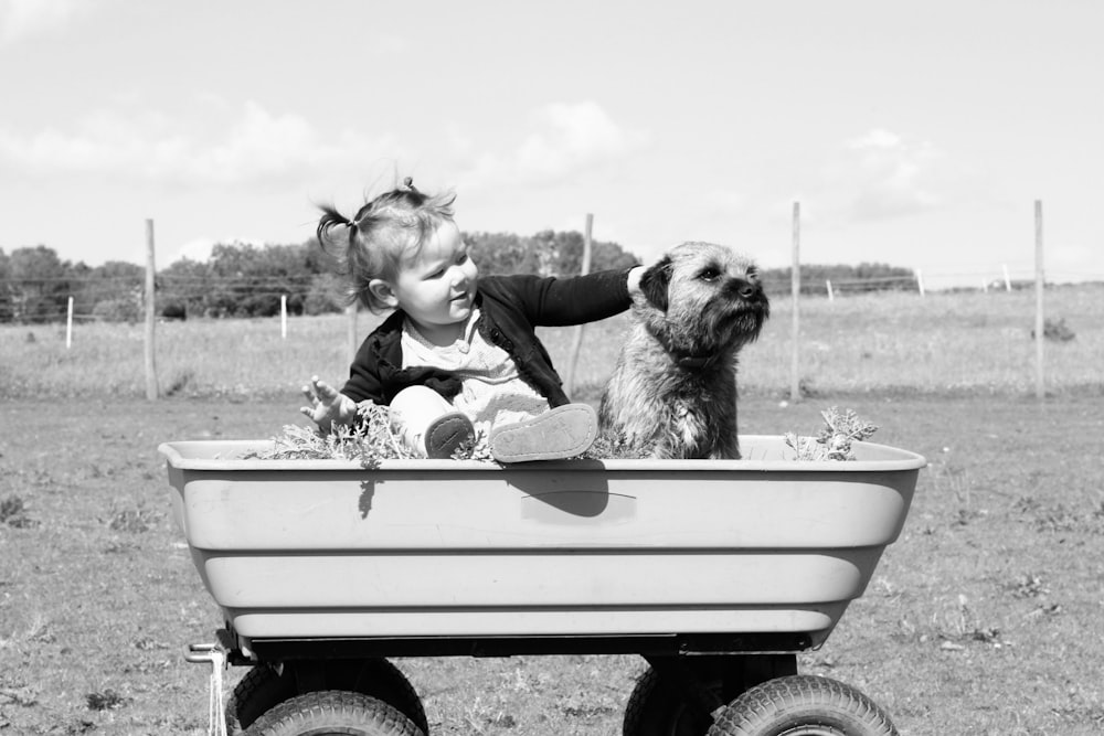 niña sosteniendo cachorro en carreta de juguete