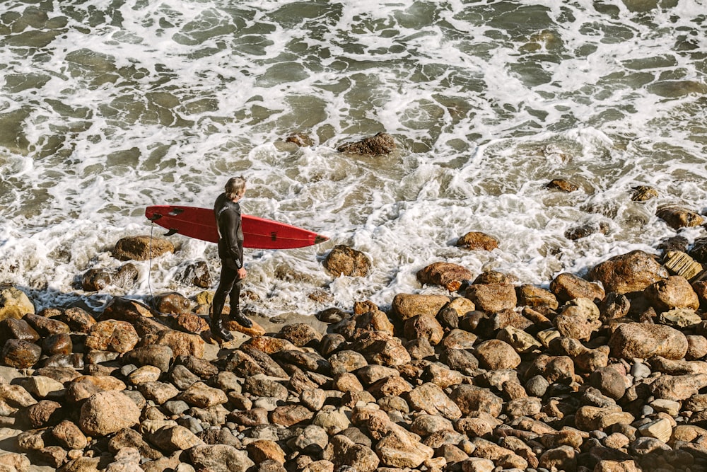 Person, die tagsüber ein Surfbrett in der Nähe der Küste hält