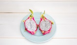 2-sliced dragon fruit in ceramic plate placed on wood plank