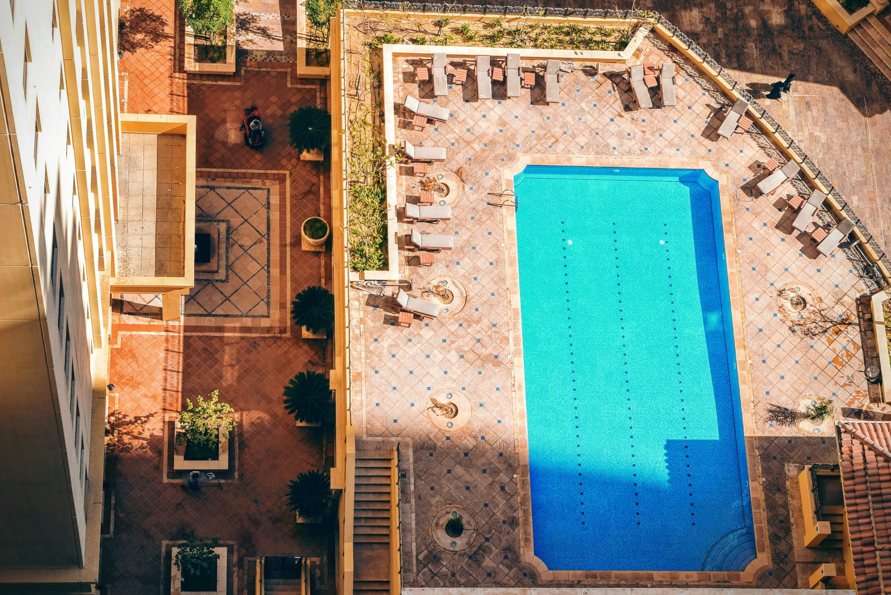 aerial photography of pool surrounded with sunlounger chairs near building