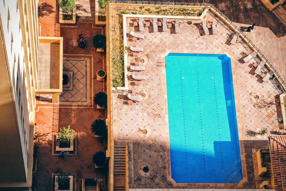 aerial photography of pool surrounded with sunlounger chairs near building