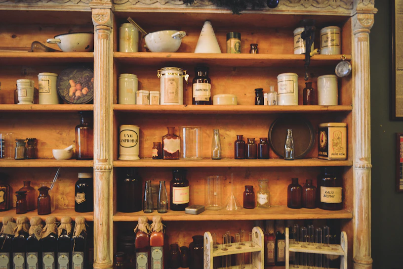 A rustic wooden shelf lined with vintage apothecary jars filled with herbs and tinctures.