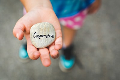 person holding stone with cooperative text cooperative teams background