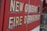 Text on the side of a vehicle reads 'New Orleans Fire Department' in bold, weathered lettering. The background is a vibrant red, typical of emergency service vehicles.