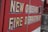 Text on the side of a vehicle reads 'New Orleans Fire Department' in bold, weathered lettering. The background is a vibrant red, typical of emergency service vehicles.