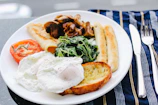 sunny side-up egg on white ceramic plate beside stainless steel butter knife and fork