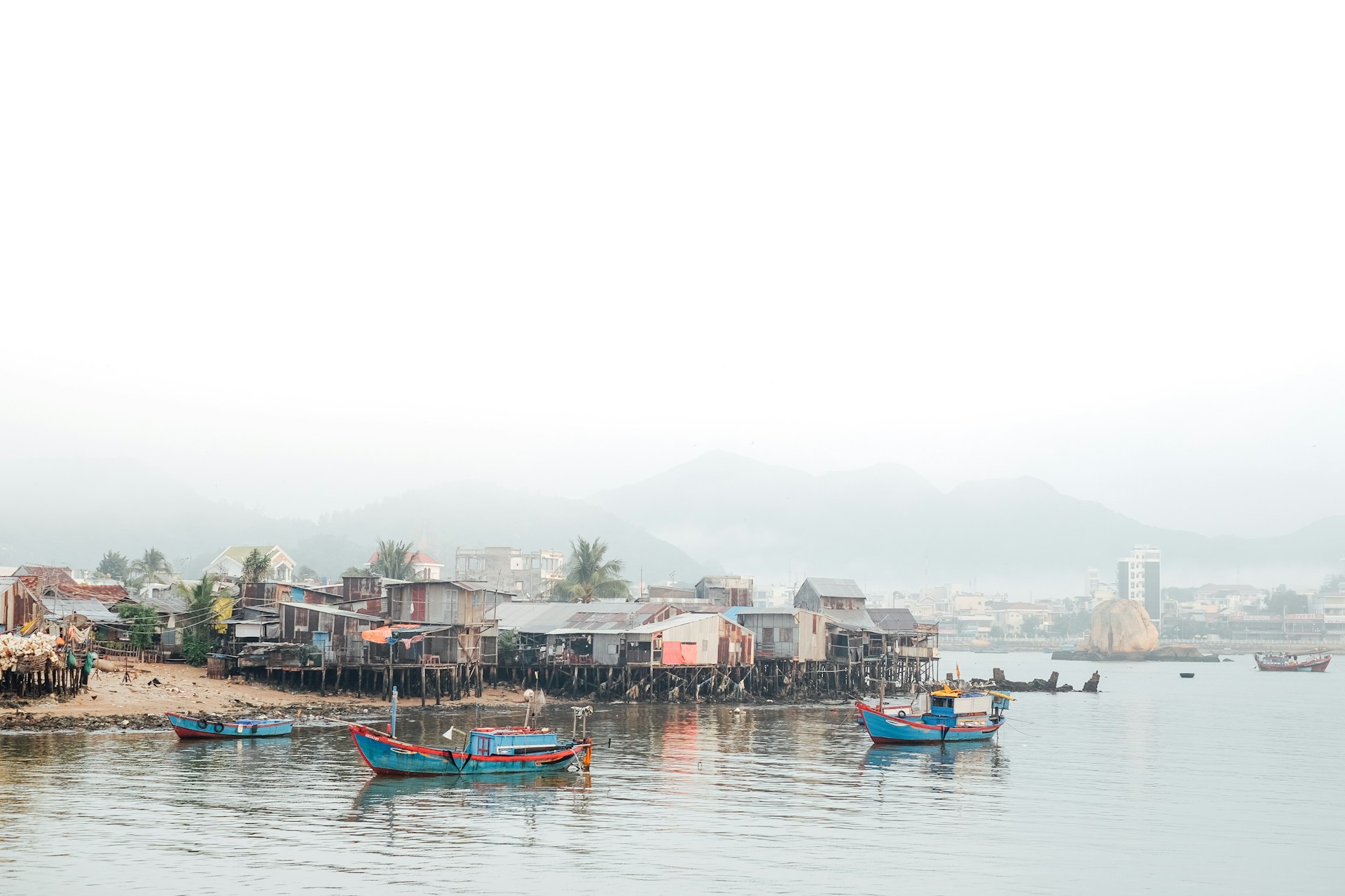 Colorful fishing boats resting on the shore of the peaceful fishing village, framed by lush greenery.