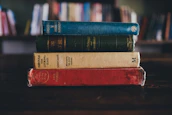 A stack of classic literature and psychology books on a wooden table.