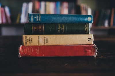 A stack of fantasy novels on a wooden table.