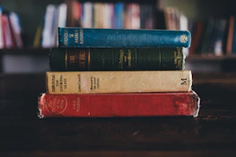 A stack of classic literature and psychology books on a wooden table.