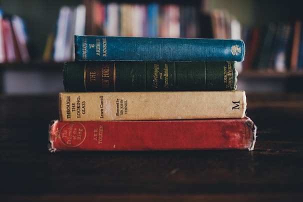 A stack of contemporary novels on a wooden table.