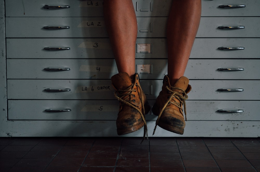 pessoa usando botas de trabalho marrom no armário