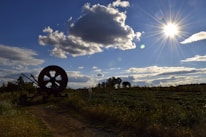 A well-maintained farm with equipment and a person checking machinery under a bright sky.