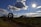 A woman inspecting farm equipment in a rural yard on a bright day.