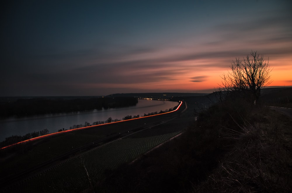 black asphalt road near body of water during sunset